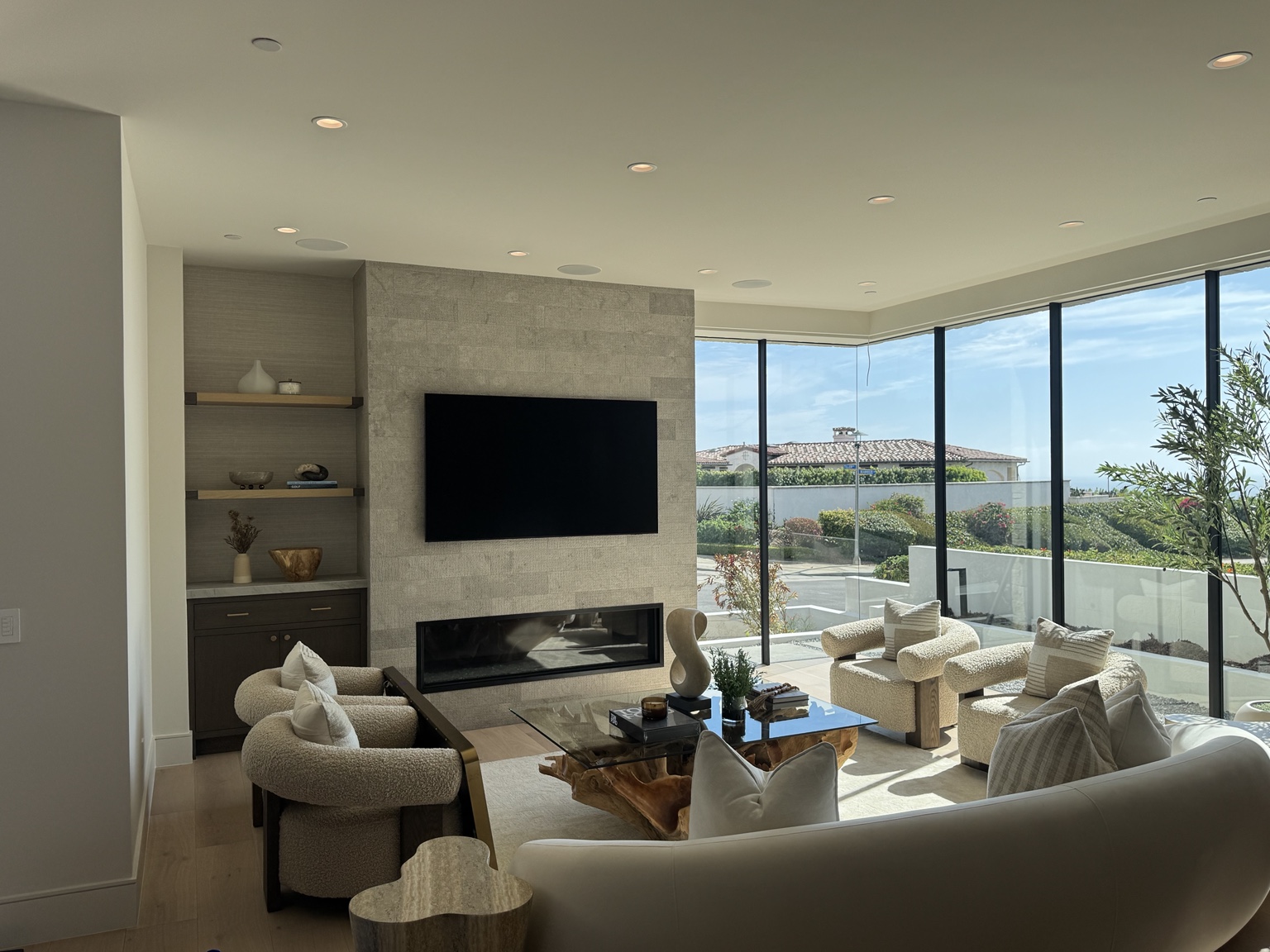 Luxury living room with recessed lighting, ceiling speakers and a clean wall-mounted television